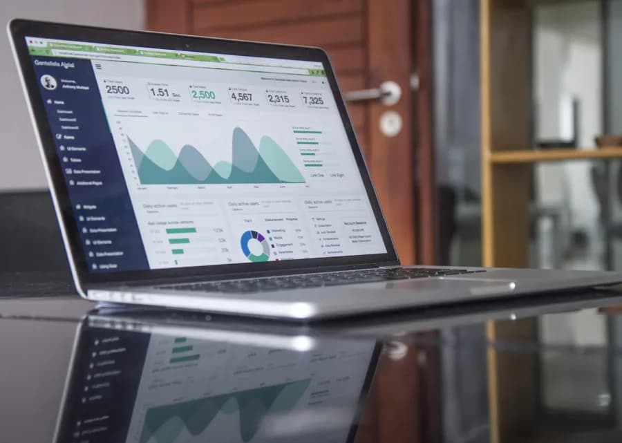 Analytics dashboard on a laptop next to a printed report on a desk